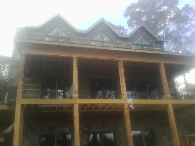 Dormers and porch framing on a large log home under construction — Roof Coating work by our crew in Napoleon