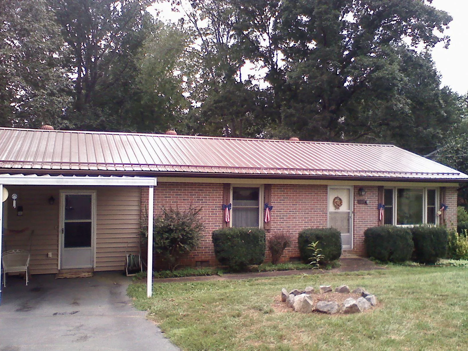 Bronze metal roof and carport on a brick ranch home — Roof Repair work by our crew in Napoleon