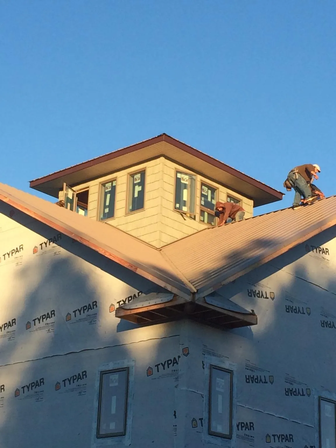 Roofers working around a rooftop cupola on a new metal roof at sunset — Roof Waterproofing in Napoleon by Roofing Brothers